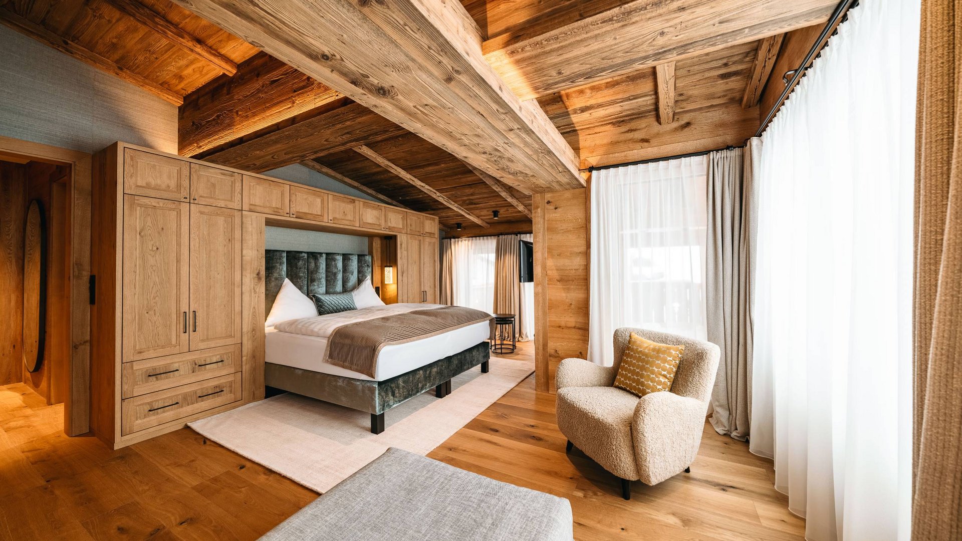 Holidays at the Arlberg: your hosts Cozy bedroom with wooden beams, bed, and armchair next to large windows