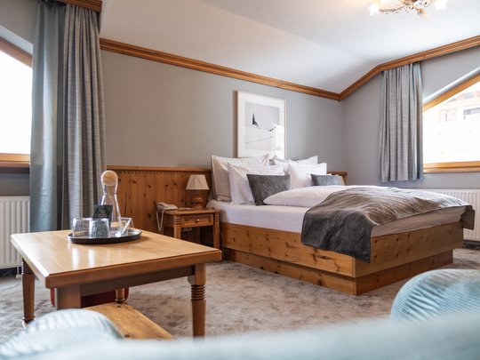 Ihr Hotel in St. Christoph am Arlberg Gemütliches Hotelzimmer mit Holzmöbeln, großem Bett und Tisch