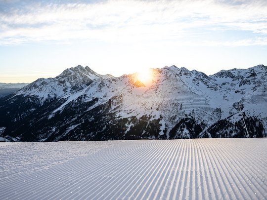 Hotel Maiensee: Wintersport am Arlberg Sonnenaufgang über schneebedeckten Bergen mit frisch präparierter Skipiste