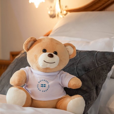 Ihre Unterkunft in St. Christoph am Arlberg: Bilder Kuschelteddy mit weißem T-Shirt sitzt auf Bett mit Kissen und Lampe