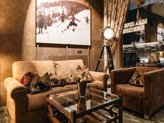 Das Maiensee: Ihr Hotel in St. Christoph Gemütlicher Sitzbereich mit braunen Sofas und Ski-Wandbild