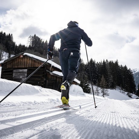 Ihre Unterkunft in St. Christoph am Arlberg: Bilder Langläufer auf verschneiter Loipe vor Holzhütte und Tannen im Winterwald