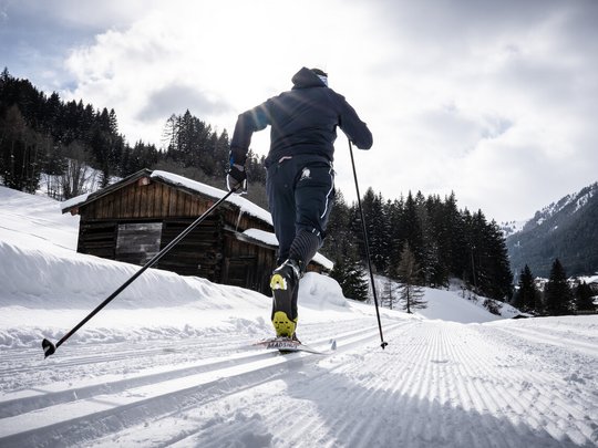 Hotel Maiensee: Wintersport am Arlberg Langläufer auf verschneiter Loipe vor Holzhütte und Tannen im Winterwald