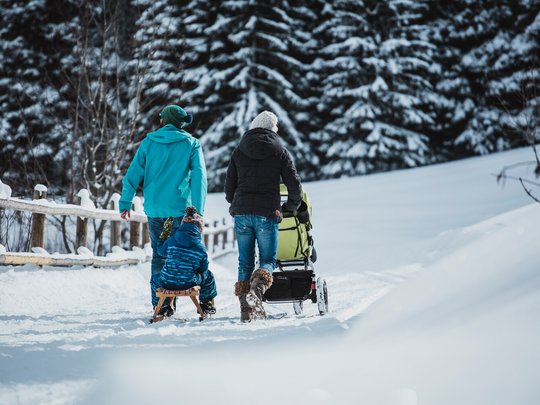 Hotel Maiensee: Wintersport am Arlberg Familie geht im Schnee spazieren, Kind sitzt auf Schlitten