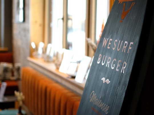 Burger im Skihotel in St. Anton am Arlberg Schild mit Aufschrift We Surf Burger in moderner Burgerbar mit Sitzplätzen