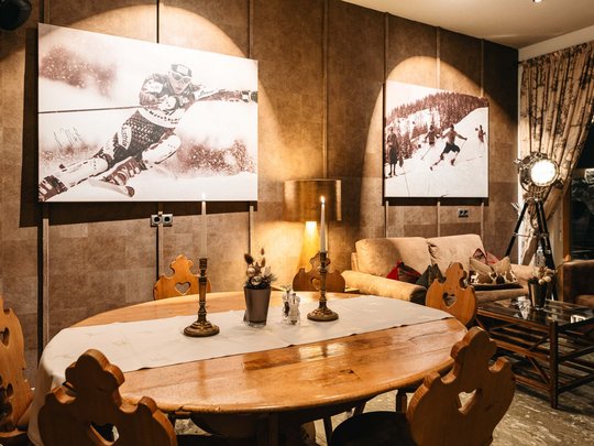 Die Lounge-Bar in Ihrem Skihotel am Arlberg Gemütlicher Essbereich mit Holztisch und Skifahrerfotografien an der Wand