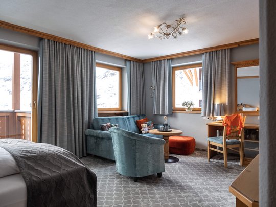 Das Maiensee: Ihr Hotel in St. Christoph Helles Zimmer mit Sofa, Sesseln, Schreibtisch und Fenster mit Vorhängen