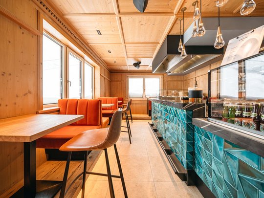 Das Maiensee: Ihr Hotel in St. Christoph Innenraum einer modernen Bar mit orangen Sitzbänken und blauer Fliesenbar