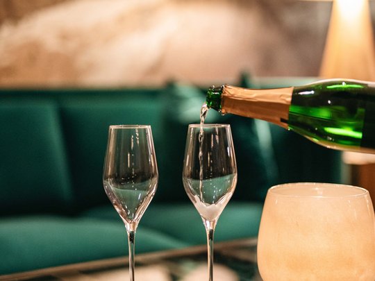Die Lounge-Bar in Ihrem Skihotel am Arlberg Sekt wird in zwei Gläser in einem gemütlichen Wohnzimmer eingegossen