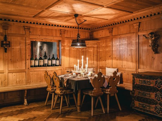 Das Maiensee: Ihr Hotel in St. Christoph Gemütlicher Holzesstisch mit Kerzen und Weinflaschen in einem rustikalen Zimmer