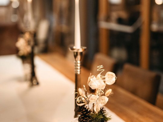 Die Lounge-Bar in Ihrem Skihotel am Arlberg Kerze und dekorative Blumentöpfe auf einem gedeckten Holztisch