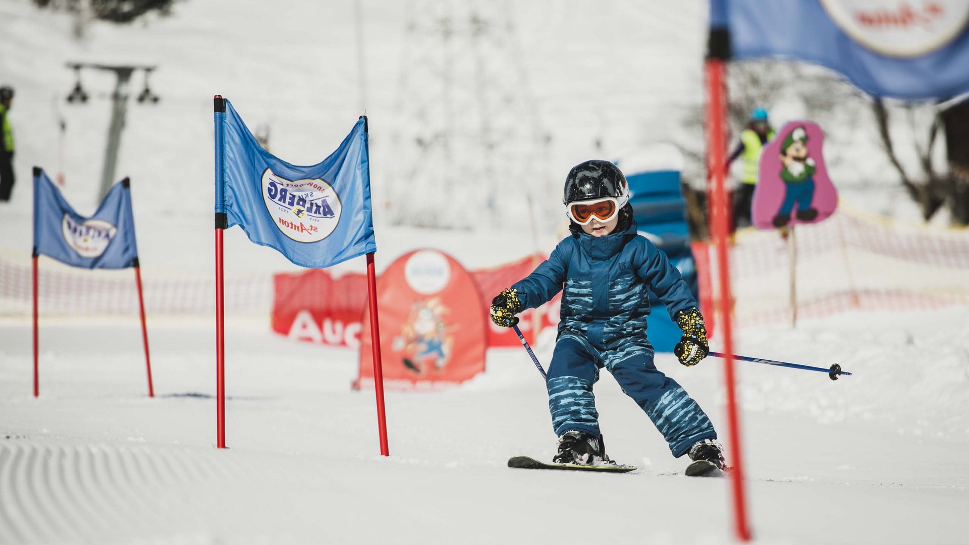 Hotel Maiensee: Wintersport am Arlberg Kleines Kind lernt Skifahren zwischen blau-roten Trainingsfahnen im Schnee