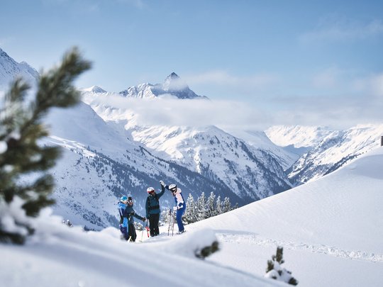 Hotel Maiensee: Wintersport am Arlberg Gruppe von Skifahrern auf verschneitem Berg mit Alpen und wolkigem Himmel im Hintergrund