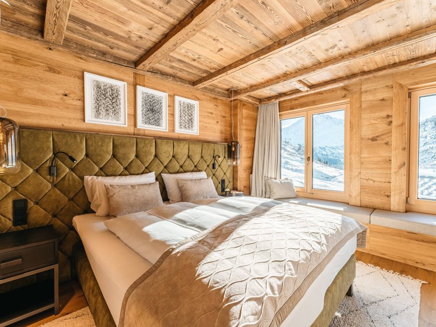 Das Maiensee: Ihr Hotel in St. Christoph Gemütliches Schlafzimmer mit Holzwänden und Bergblick durch große Fenster