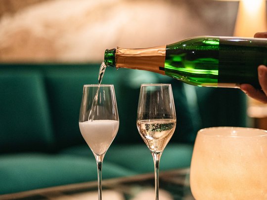 Das Maiensee: Ihr Hotel in St. Christoph Sekt wird in zwei Gläser auf einem Glastisch in einer gemütlichen Umgebung eingeschenkt