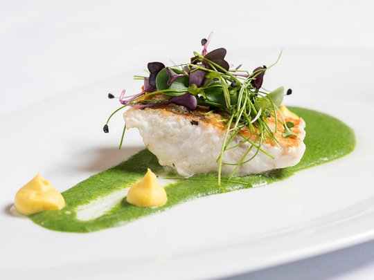 Das Maiensee: Ihr Hotel in St. Christoph Gebratenes Fischfilet mit grüner Sauce, Kräutern und zwei kleinen Dips auf weißem Teller