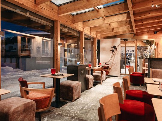 Das Maiensee: Ihr Hotel in St. Christoph Gemütliches Café mit Holzdecke und großen Fenstern mit Blick auf verschneite Straße