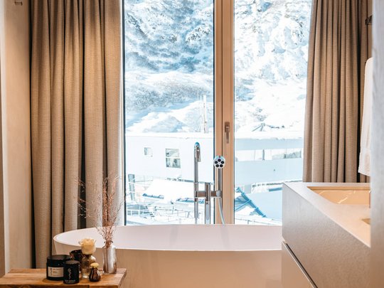 Ihr Hotel in St. Christoph am Arlberg Moderne Badewanne mit Blick auf schneebedeckte Berge durch Fenster