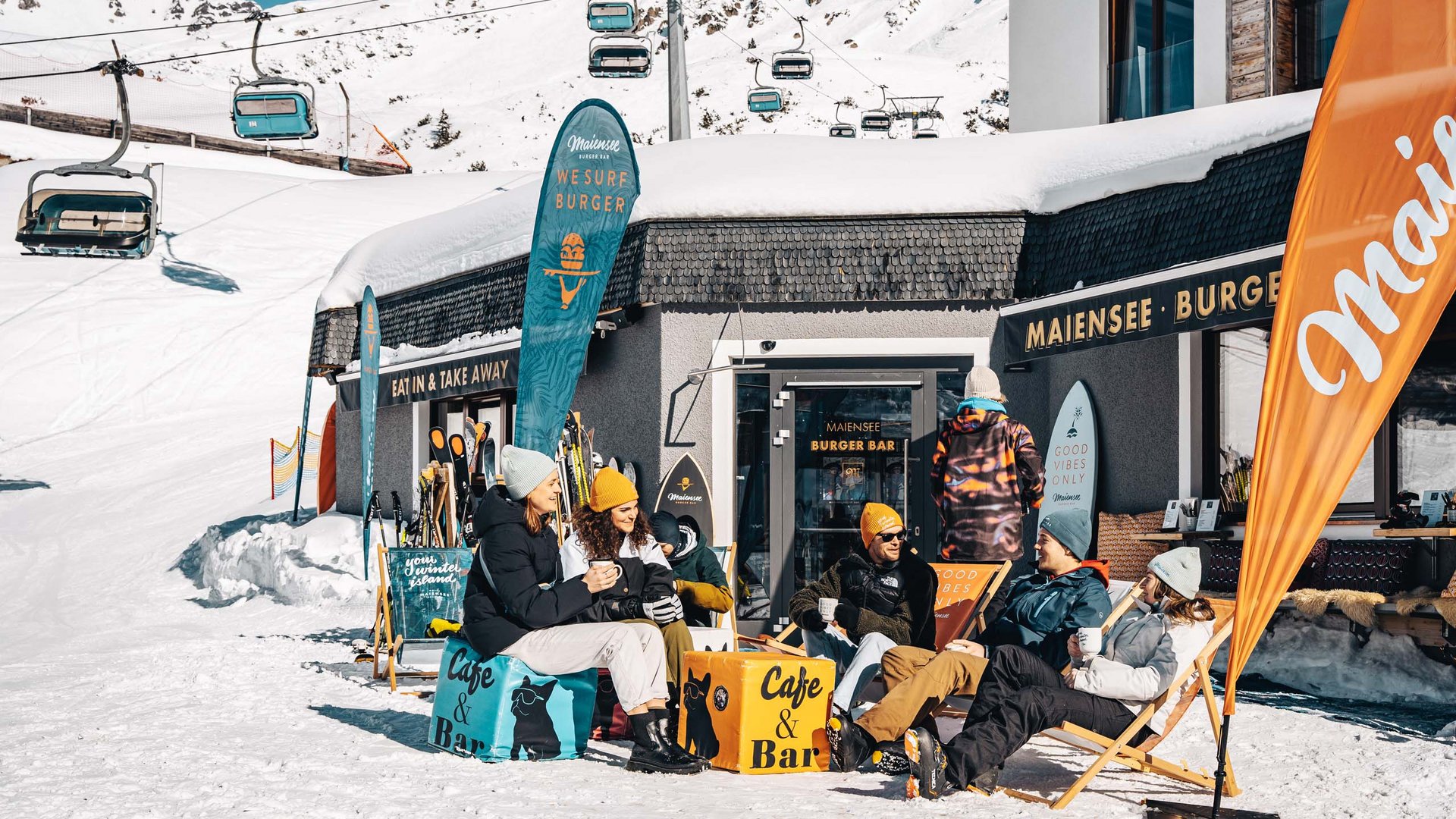 Burger im Skihotel in St. Anton am Arlberg Gruppe von Menschen sitzt vor einem Bergcafé im Schnee